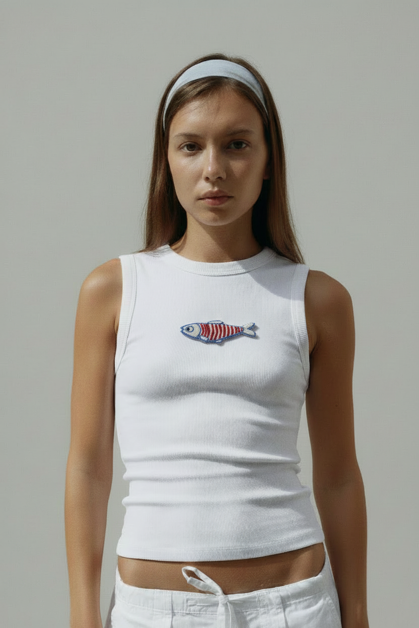 Front-facing model wearing white ribbed top with blue and red fish beadwork