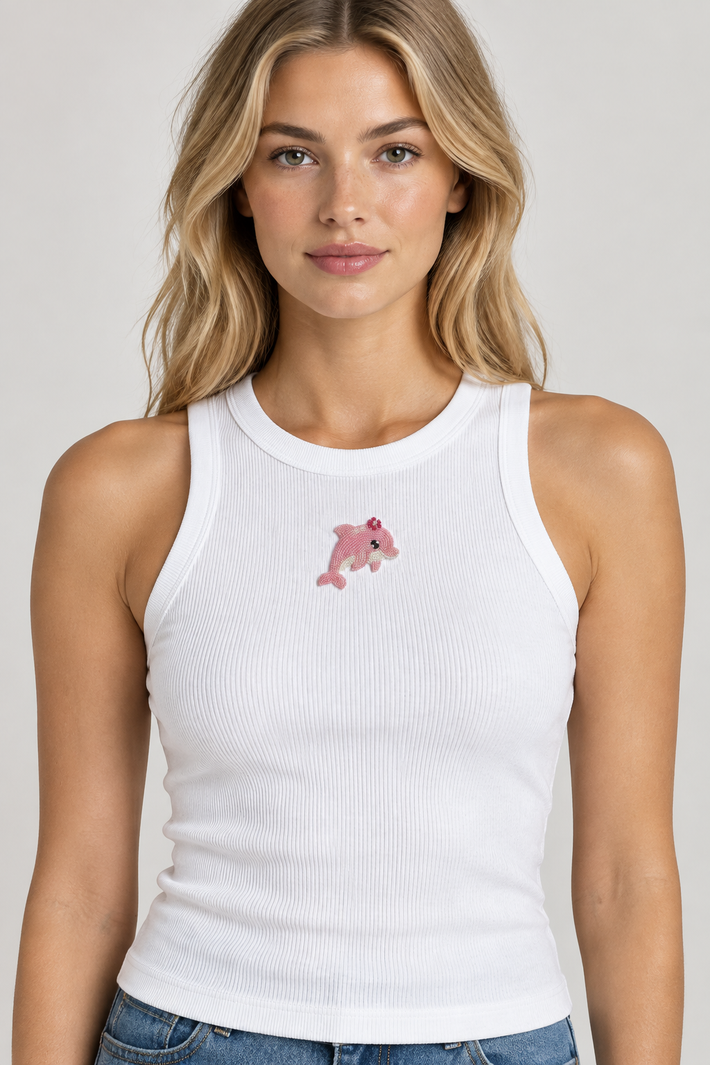 Model wearing white ribbed top with pink beaded dolphin, front view