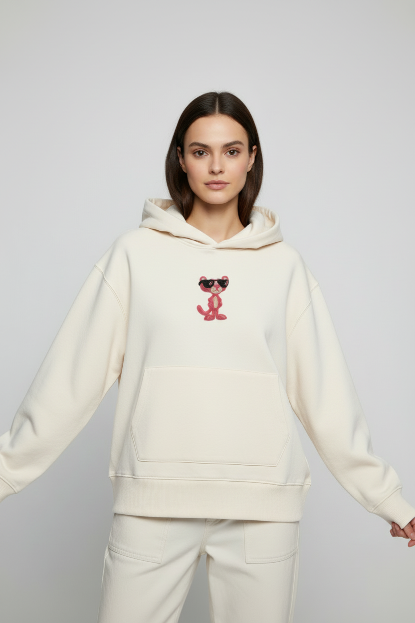 Front-facing model wearing a cream hoodie with Pink Panther beaded appliqué centered on the chest