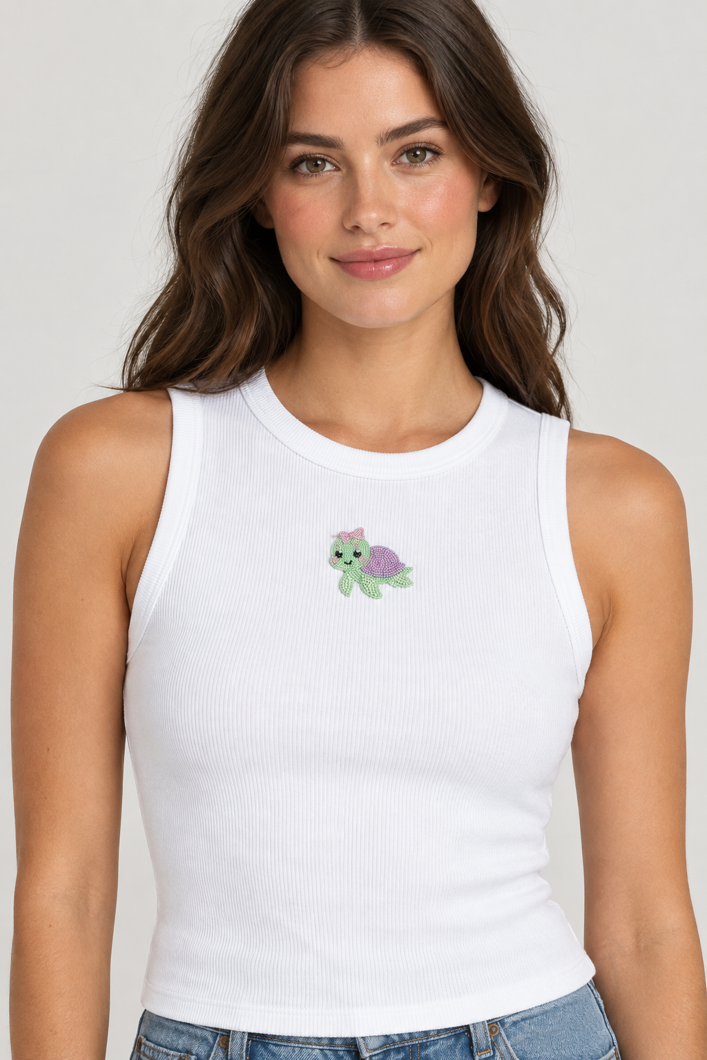 Model wearing white ribbed top with beaded turtle, front view